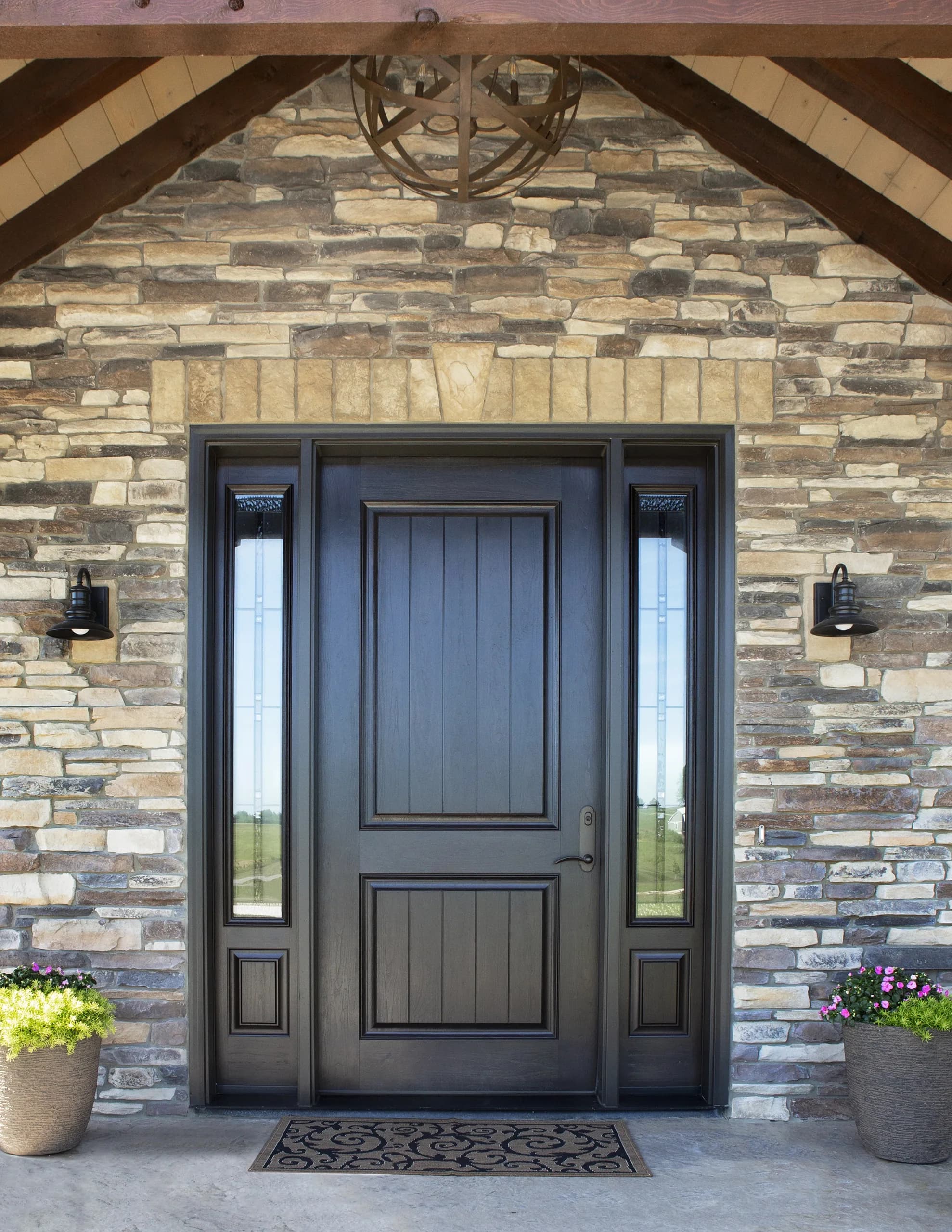 A black entry door set in a stone and timber-frame home in Western Colorado