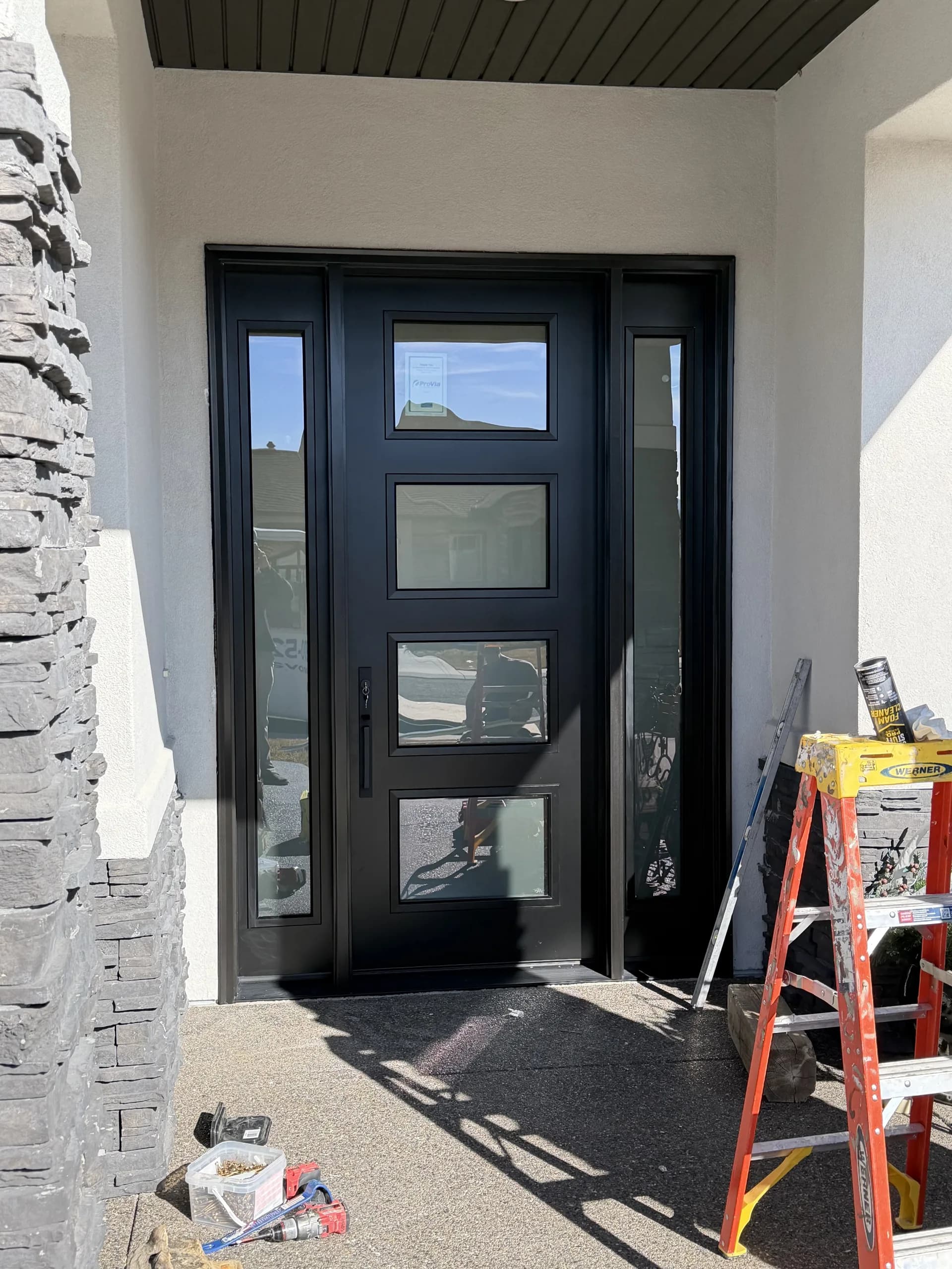 Modern black commercial door with frosted glass panel in stone surround, suitable for fire-rated assembly